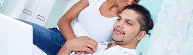 Image of young girl kissing her boyfriend using laptop